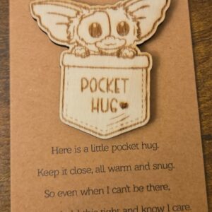 Engraved basswood cute creature pocket hug displayed on a small keepsake message card
