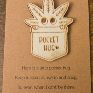 Engraved basswood leafy character pocket hug displayed on a small keepsake message card