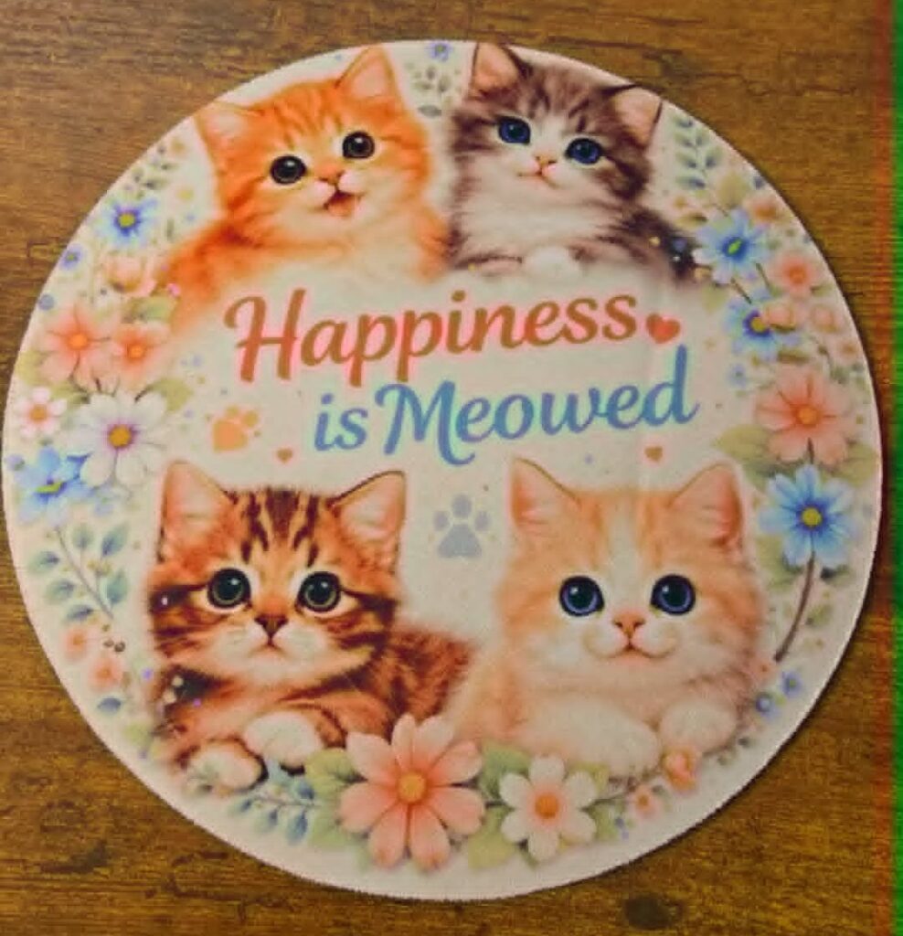Round cat-themed mousepad reading Happiness Is Meowed